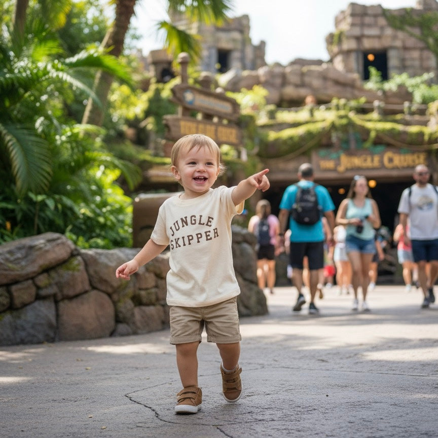 Child wearing a 'Jungle Skipper' shirt pointing at an attraction in a theme park.